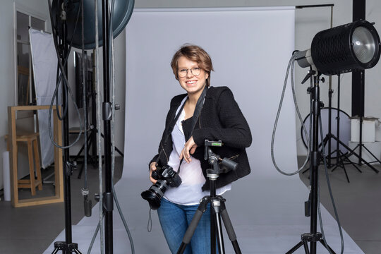 Portrait of smiling young photographer with equipment at photographic studio