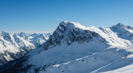 Fototapeta premium Majestic snow-covered mountain peaks under clear blue sky in winter wonderland scene