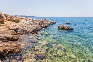 Crystal Clear Waters and Rocky Shoreline in Greece, Sunny Summer Day