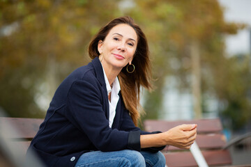 stylish woman sitting on a park bench