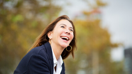 woman caught in a candid moment, laughing in an autumn park