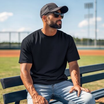 Men's black t-shirt mockup. Middle aged man in baseball cap sitting on bench in stadium. Sports man, player, coach, dad, father. Regular short sleeve tee. Urban, sport lifestyle casual tee
