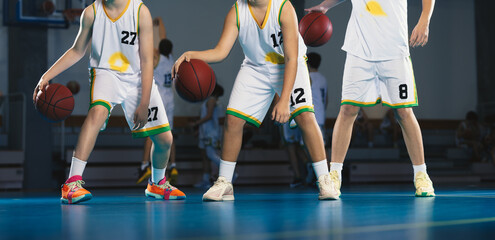 Junior level basketball players bouncing basketballs together. Young basketball players with...
