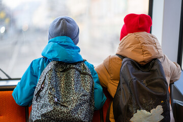 Two schoolchildren go to school in the backseat of public transport