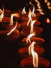Close-up of candles with flickering flames in a dark setting. Thailand