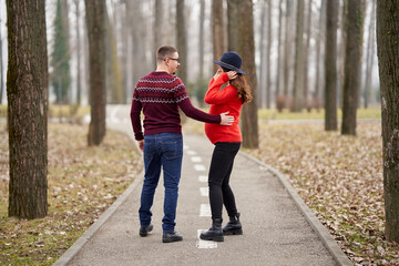 Fototapeta premium Expecting couple walking hand in hand outdoors