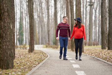 Fototapeta premium Expecting couple walking hand in hand outdoors