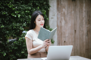 Obraz premium Confident Asian woman working on laptop outdoors. She embraces technology and freelancing, modern entrepreneurship, e-banking and urban success with determination and efficiency.
