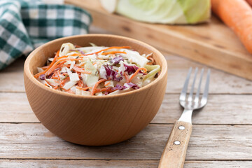 Coleslaw salad in wooden bowl on wooden table. Copy space