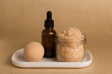 Natural body scrub in a jar, bubbling ball for a bath, bottle on a stand composition on a brown background