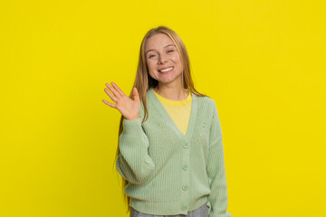 Young Caucasian woman smiling friendly at camera, waving hands gesturing hello greeting or goodbye welcoming with invitation hospitable expression. Pretty girl isolated on yellow studio background