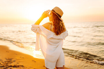Young woman enjoys her vacation on the beach. Seascape at sunset with beautiful sky. Travel,...