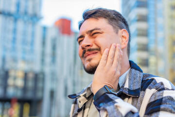 Mature Caucasian man tourist standing on downtown city street feeling toothache bad unpleasant...