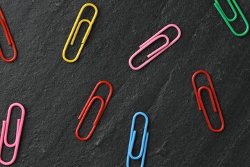 Many colorful paper clips on black table, flat lay
