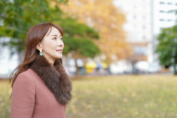 Naklejka premium A woman with long hair in her thirties stands in a beautiful autumn leaves in a beautiful autumn leaves