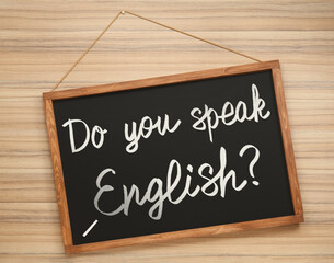 Small black chalkboard with text Do You Speak English? on wooden background, top view. Language...