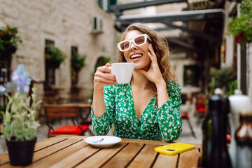Young stylish woman having a breakfast with coffee sitting outdoors at the cafe terrace. Food and drink. People, fashion, lifestyle, travel and vacations concept