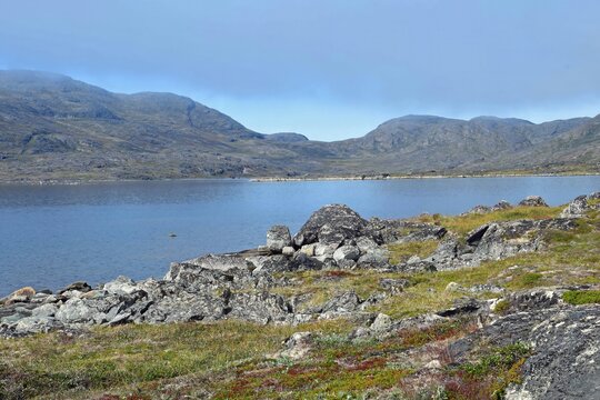 Hiking along lake taseruaq with   the pingu mountain peaks in the background in  the   fishing village of qarqortoq, in western greenland, on a sunny summer day