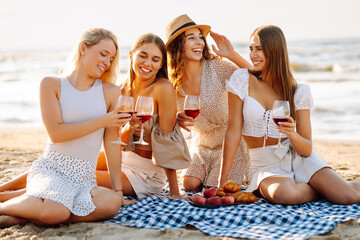 Beach party. Group of young women with wine glasses having fun on the beach, celebrating hen party...