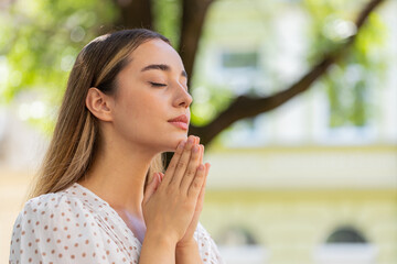 Portrait of young woman praying with closed eyes to god asking for blessing, help, forgiveness...