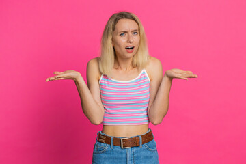 What. Why. Angry confused young woman in crop top raising hands in indignant expression, asking...