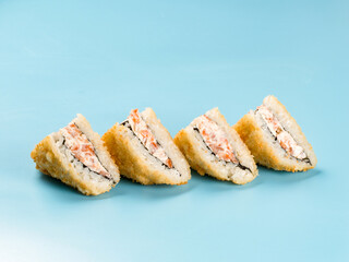Hot tempura onigirazu with salmon mousse on blue background. Onigirazu is sushi sandwich or burger roll.