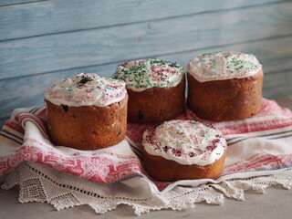 Spring Blue New Rustic baking of traditional Easter cakes for orthodox Easter. Cupcakes with white icing and colored sprinkles on a blue wood background. Romantic wedding national dessert