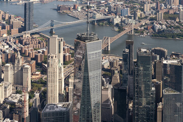 Fototapeta premium Aerial view of Manhattan skyline showcasing iconic skyscrapers, the Brooklyn and Manhattan Bridges, and the East River on a clear summer day.