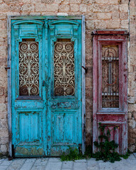 Old, colorfully painted, antique, vintage wooden doors removed from a building and lying against a stone wall in Jaffa, Israel.