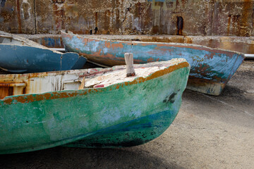 Old, weathered, wooden row boats no longer in service, painted in blue and green marine colors, at the Jaffa Port in Jaffa, Israel.