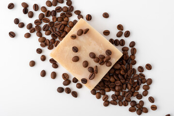 Handmade soap bar with coffee beans scattered on a white background