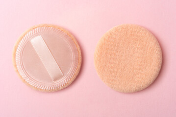 Makeup powder puffs on a pastel pink background
