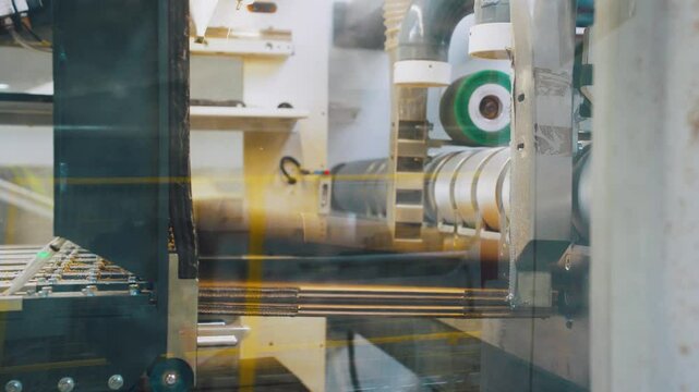 Equipment, machine producing cardboard boxes, packaging factory. Pattern, cut corrugated cardboard stacks into pallets automatic machine. Cardboard packaging factory, modern line of folding packaging