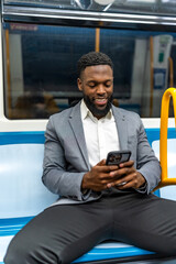 Young businessman using smartphone while sitting on subway train