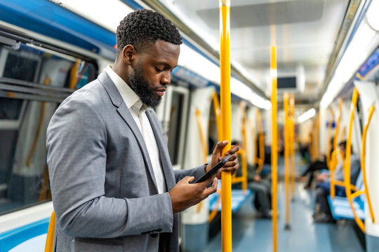 Businessman using smartphone on public transport standing on subway train