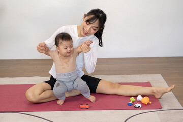 Fototapeta premium Multitasking mother helping her baby stand up, enjoying playful moments together during playtime at home