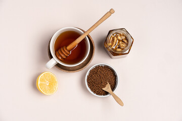 Buckwheat chinese granulated tea in a wooden bowl, honey with nuts and lemon on a light background with copy space