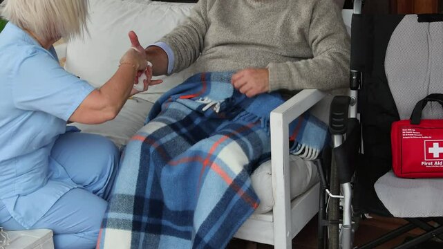 Nurse bandaging elderly man's hand