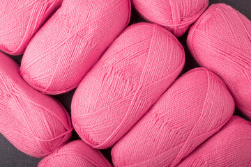 several skeins of bright pink acrylic yarn for crocheting or knitting. Flat lay close up shot, top view