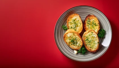 Tasty crispy garlic bread in plate on red background © HeyRix