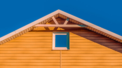 roof of a pink farmhouse wooden house against a blue sky