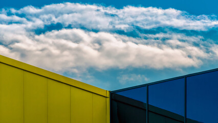 Obraz premium corner of a modern building with a window and a blue sky with clouds