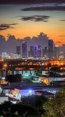 Obraz premium Cityscape Shines Under a Dramatic Sunset Sky with Illuminated Buildings and Trees Below