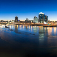 Obraz premium Cityscape Reflects in River at Twilight, Illuminating the Urban Landscape Beautifully.