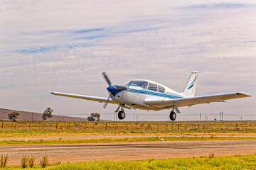 Classical style blue and white single engine aircraft with four seats taking off from airstrip in the Western Cape, South Africa
