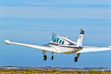 Light six-seat aircraft with wing tanks and retracting undercarriage taking off from airstrip in the Western Cape, South Africa