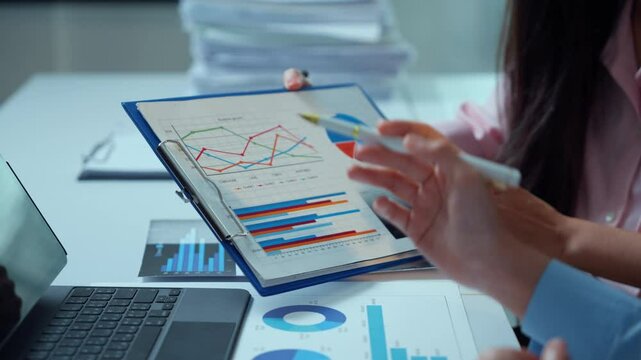 Professional team members reviewing financial metrics, sharing data driven insights, brainstorming strategy in modern corporate workspace with graphs and charts