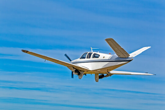 Rear view of six-seat white aircraft with black and blue stripes with unusual V shaped tail against blue sky in the Western Cape, South Africa