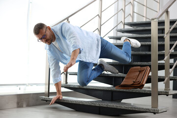 Fototapeta premium Man falling on stairs in building. Dangerous accident