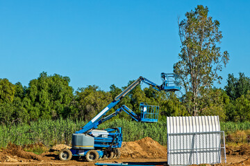 Obraz premium Two blue, mobile, battery powered cherry pickers with extending booms on a building site